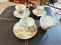 Four assorted floral porcelain demitasse/teacups with two saucers displayed on table