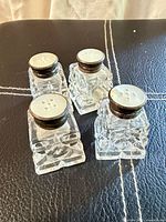 Four vintage cut glass shakers top view showing ceramic lids