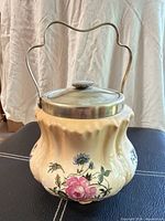 Front view of cream floral biscuit jar with lid and handle