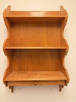 Front view showing entire oak veneer wall shelf unit with three shelves and drawer