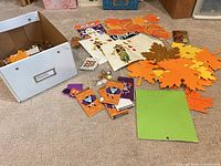 Lot overview showing box, leaf cutouts, pumpkins, notebooks and other items spread out
