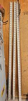 Three white slotted shelf uprights leaning against wall