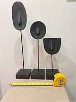 Front view of all three sculptures with tape measure for scale