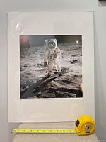 Front view of framed and matted Apollo astronaut photographic print with tape measure showing dimensions
