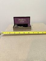 AutoStrop case open showing interior logo and razor inside, tape measure for scale