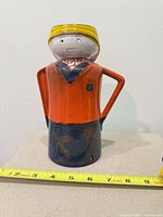 Front view of ceramic figurine vase-pitcher with tape for scale