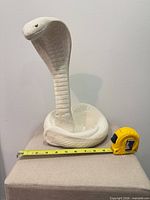 Front view of ceramic cobra with measuring tape for scale