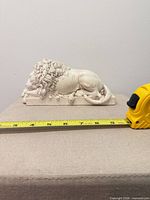 Sleeping lion figurine profile view with tape measure indicating length