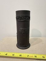 Full front view of cylindrical black basalt vase beside measuring tape