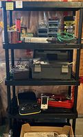 Full view of four-shelf black plastic shelving unit loaded with tools and accessories