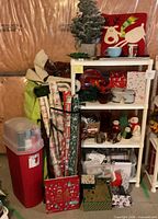 Full view of loaded 3-tier shelf, wrapping paper rolls, storage bin and assorted decorations