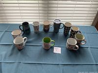 Full set of eleven assorted mugs on table