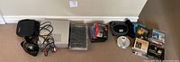 Overview of lot lined against wall showing players, remotes tray, CDs, cables, cases