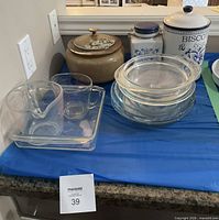 Overall lot showing glass bakeware, measuring cups, nested pie plates and ceramic canisters
