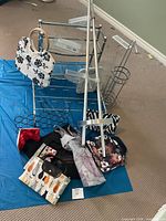 Overview of lot showing shelving parts, crutches, racks, and assorted handbags on blue sheet