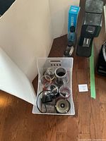 Bin containing various Nutribullet/Magic Bullet cups, lids, blades, power cord