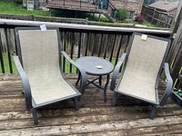 Two aluminum lounge chairs and side table on deck