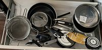 Drawer view showing entire lot of pans, lids, strainers