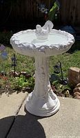 Full view of white painted concrete bird bath on pedestal