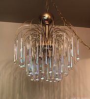 Full view of chandelier hanging, showing brass frame and teardrop prisms