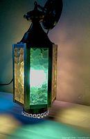 Full view of lantern illuminated showing multicolour glass panels and metal cap