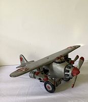 Front left perspective of cast iron airplane showing propellers, pilots, landing gear
