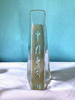 Front view of clear glass obelisk showing runic engravings on gold background