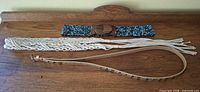 Three belts laid out: beaded with wood buckle, macramé, skinny leather