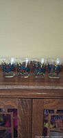 all four decorated tumblers on cabinet showing full design