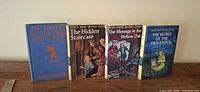 All four Nancy Drew books standing in a row, showing covers and spines