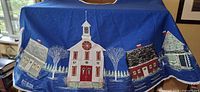 Full view of round blue tree skirt with village appliqué