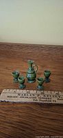 front view of carafe and four goblets beside ruler for scale