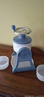 Front view of blue and white Pampered Chef ice shaver with two white plastic ice molds