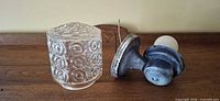 Glass shade and metal fixture components side by side