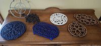 Seven assorted trivets on wooden surface