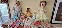 Full lot view showing all dolls, clothing, accessories on table