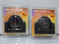 Front view of two packaged pedestal quartz clocks