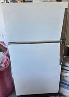 Front view of white Amana top-freezer refrigerator with wood-trim handles