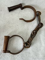 Full view of connected iron handcuffs showing both cuffs and chain links