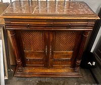 Front view of cabinet showing marble top, drawer, doors, columns