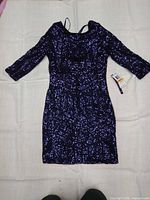 Front view of dress laid flat showing entire garment, sleeves, length and attached retail tags