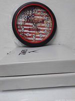 Clock with American flag face resting on two white product boxes