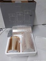 Box with foam insert holding three bubble-wrapped candles and remote