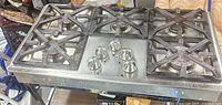 Top view showing full cooktop, five burners, center controls, cast iron grates with visible crack on front left grate