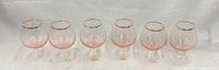 Full set of six pink Bohemia brandy snifters with gold rims displayed in a row