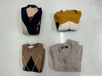 four folded sweaters showing variety of colors and patterns