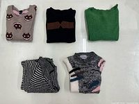 Five folded XL women’s knitted sweaters with varied colors and patterns