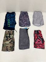 Six of the thirteen swim trunks laid flat showing assorted patterns and colors