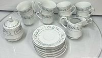 Complete 17-piece Sango Garden Flower china set: 8 teacups stacked, 7 saucers, creamer, lidded sugar bowl