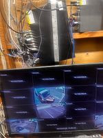 Monitor displaying multiple camera feeds, DVR units and wiring visible